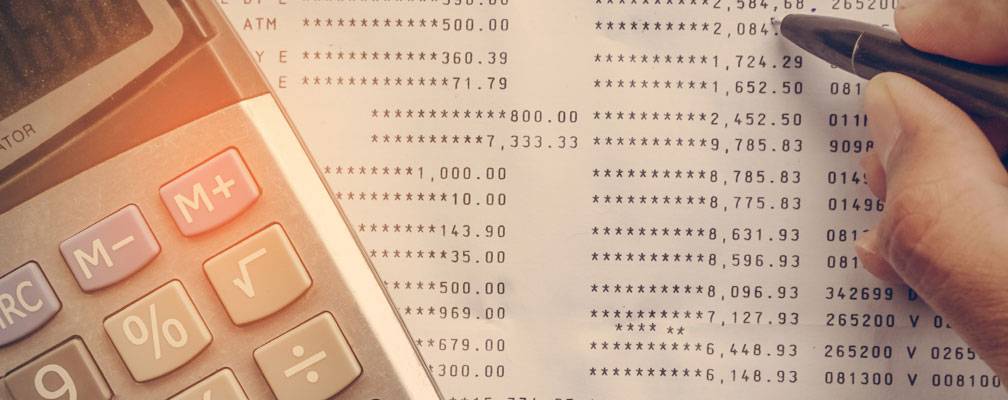 calculator on top of a bill with someone holding a pen