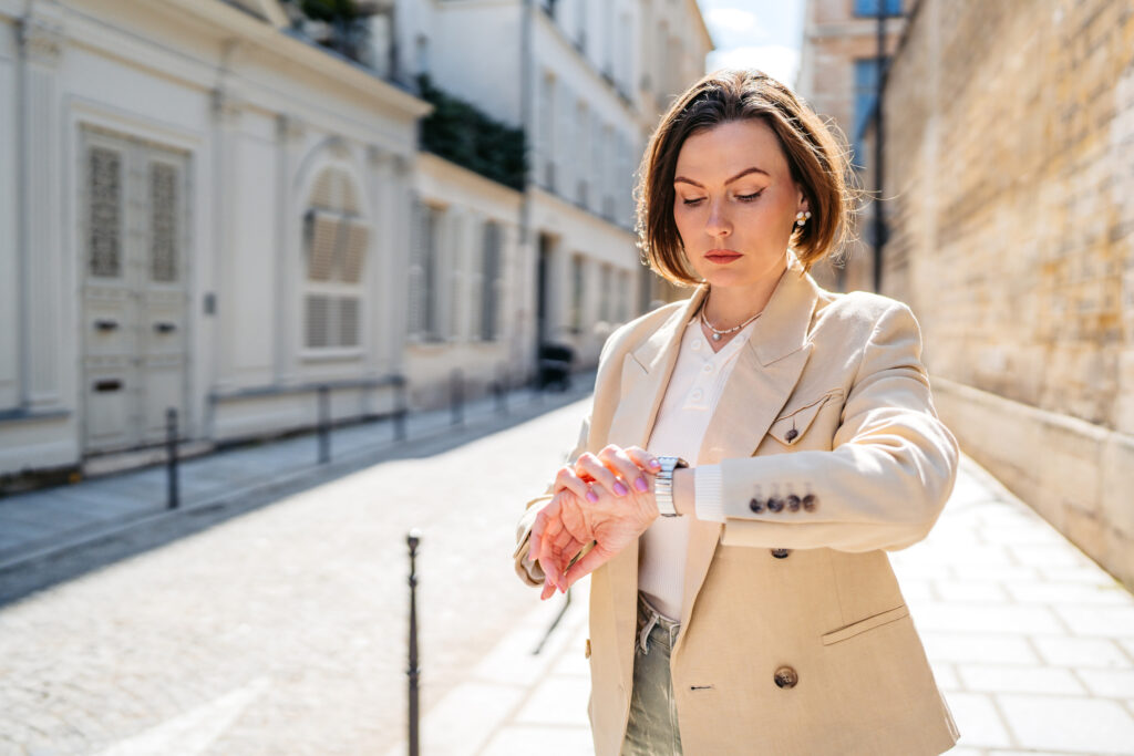 lawyer walking down a sidewalk outside looking at watch on wrist